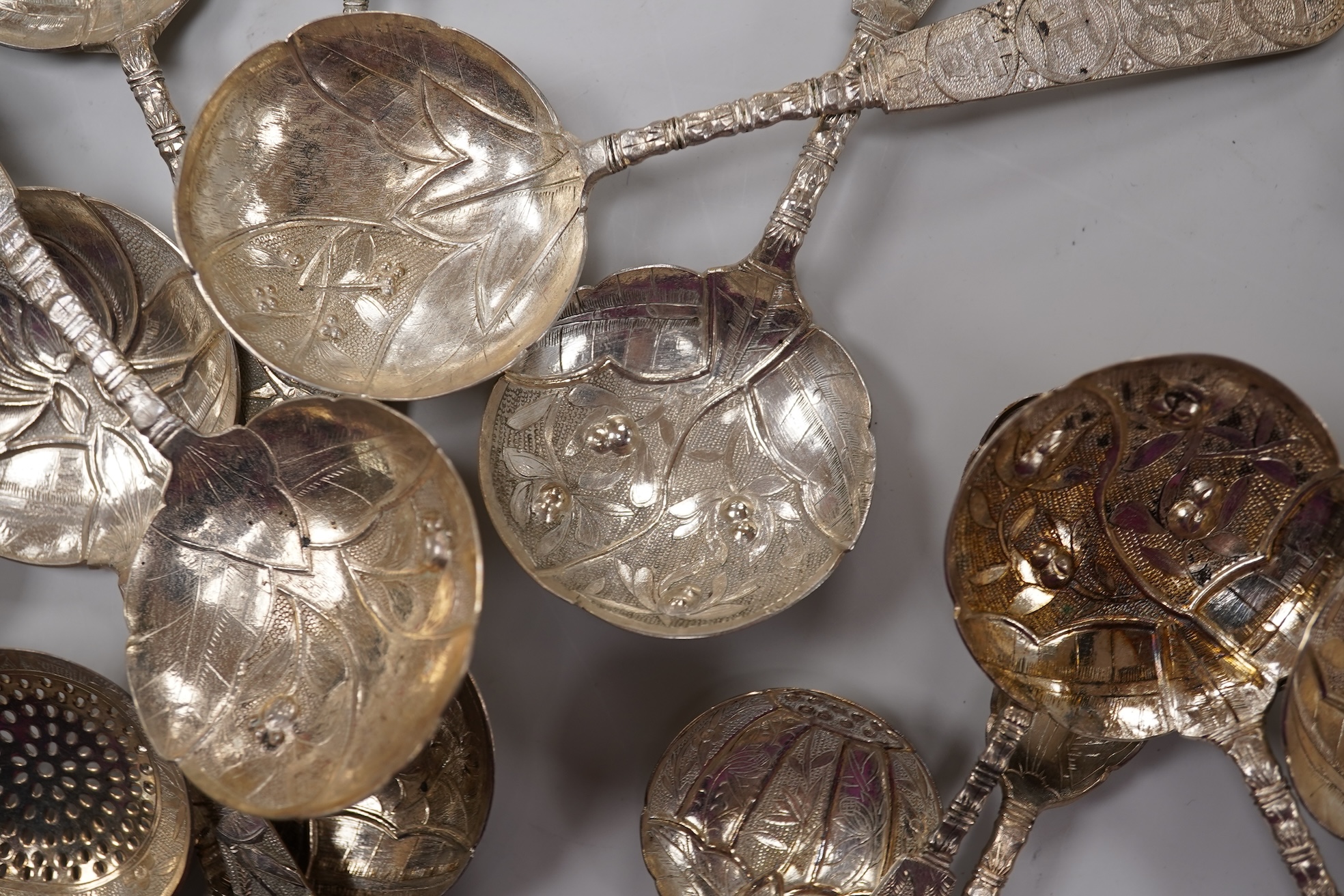 A set of twelve early 20th century Chinese Export white metal small spoons, maker LS, decorated with foliage and character mark, 10cm, a set of ten similar larger spoons, same maker, 12.3cm and another set a six similar